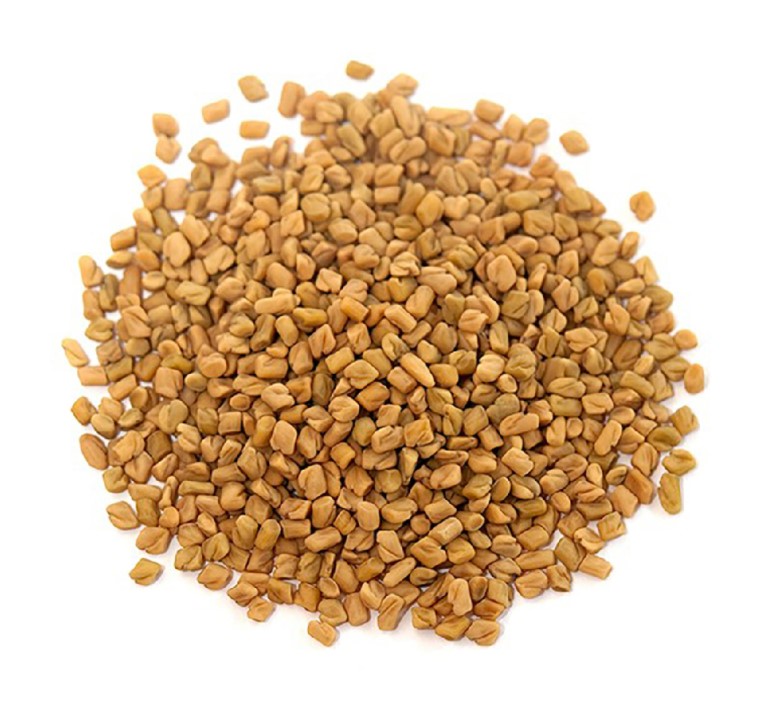 a domed circle of light brown, orange coloured fenugreek seeds in a circle with a white background