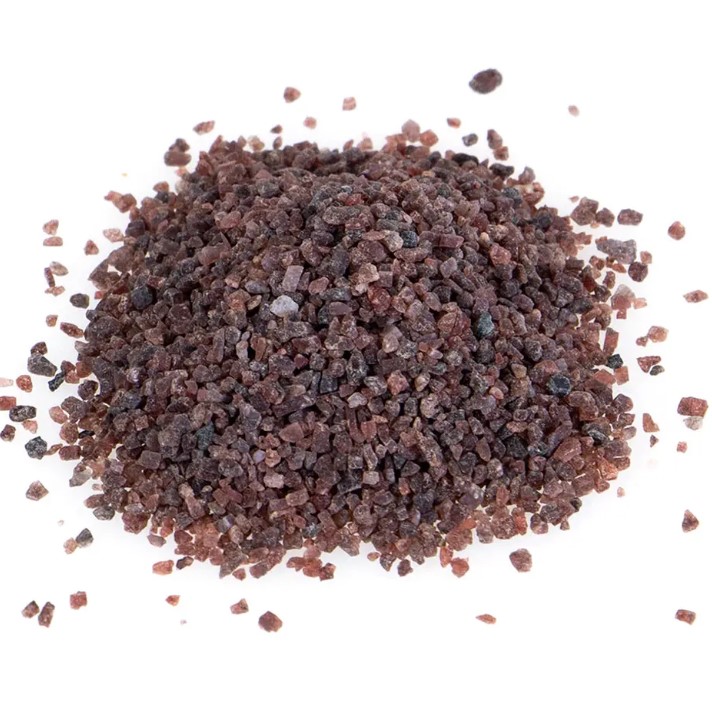 A pile of dark purple and black Himalayan black salt with a white background