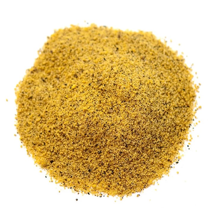 A round pile of yellow pepper seasoning on a white background