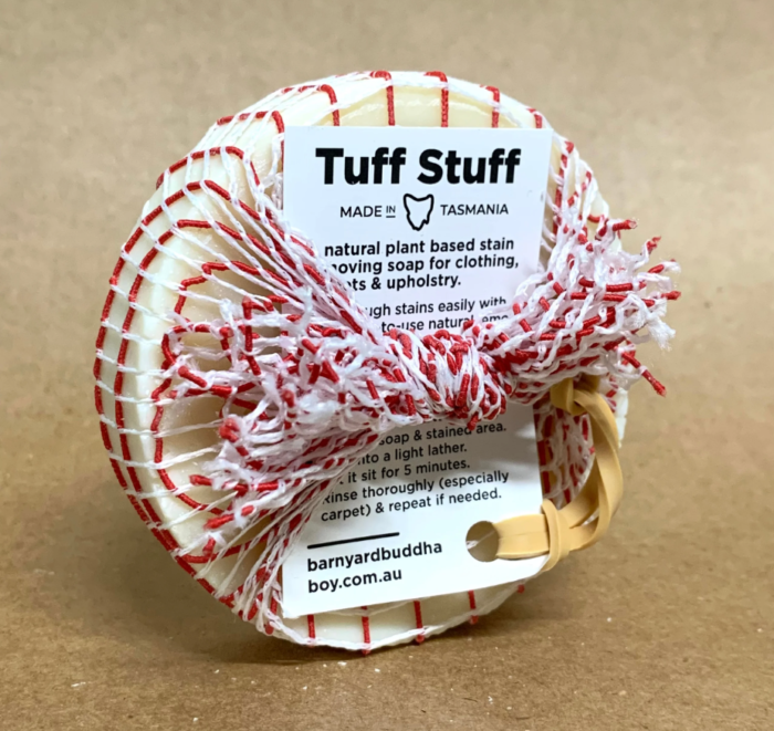 Round soap that is standing up on its edge, covered in a red and white strip cotton mesh